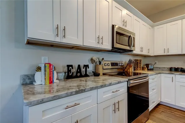 a kitchen with granite countertop white cabinets stainless steel appliances and a sink