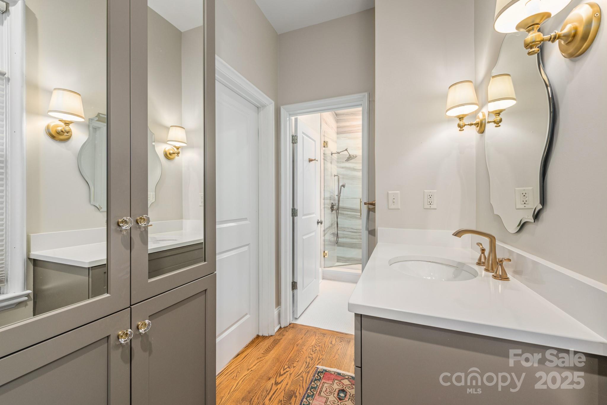 1025 Ardsley Road, Unit 104 Charlotte, NC 28207 - Photo 24 of 30 a bathroom with a sink a mirror and shower