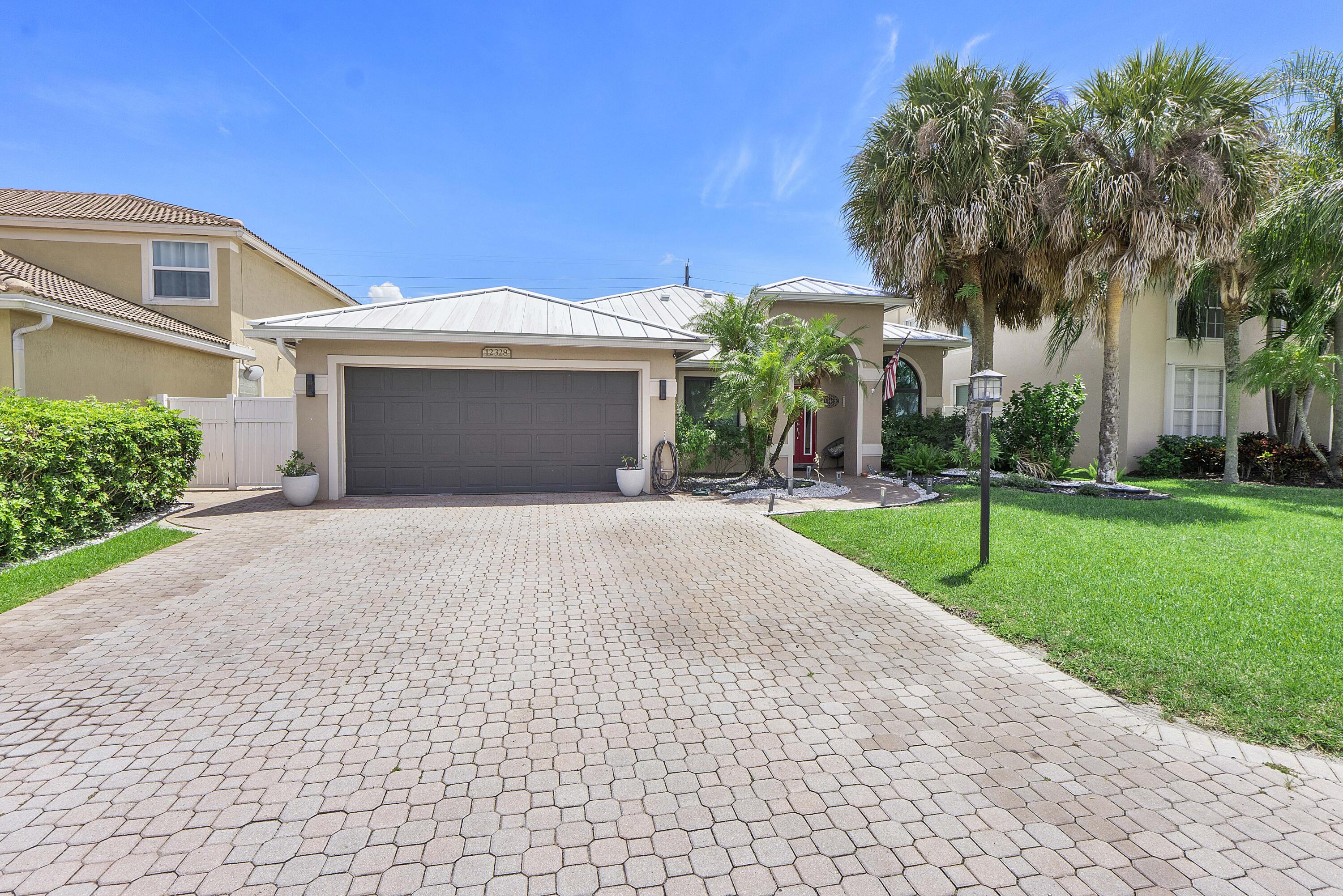 12328 St Simon Drive Boca Raton, FL 33428 - Photo 2 of 52 a front view of a house with a yard and trees