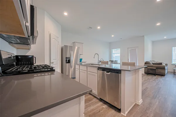 a kitchen with stainless steel appliances granite countertop a white table and chairs