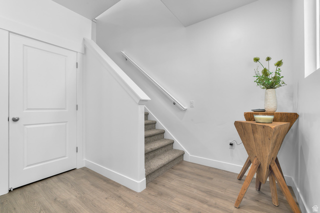 2819 South 710th West, Unit 14 Logan, UT 84321 - Photo 7 of 24 Laminate wood-finish flooring, two-panel interior door with brushed nickel hardware, carpeted staircase, white wall trim, and a handrail