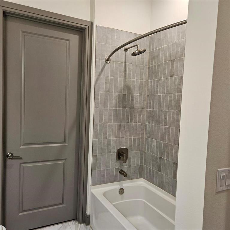 2700 Old Denton Road, Unit 2238 Carrollton, TX 75007 - Photo 15 of 21 Tub/shower combination featuring vertical rectangular tile surround, brushed nickel fixtures, and a curved shower rod