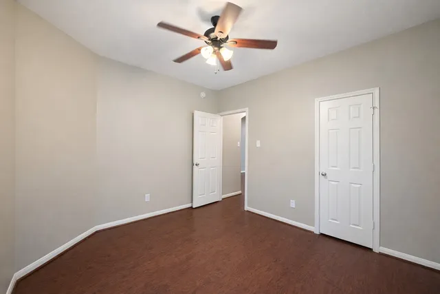 an empty room with a chandelier fan and windows