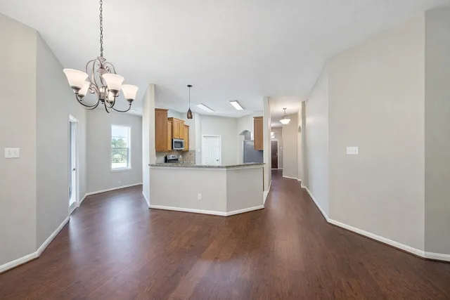 a view of a hallway with wooden floor and a kitchen