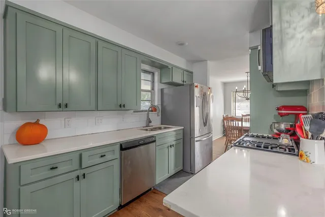 a kitchen with stainless steel appliances granite countertop a sink dishwasher stove and refrigerator with wooden floor