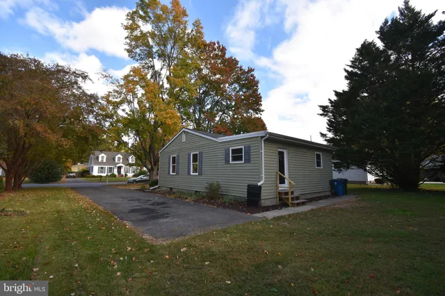 a view of a yard in front of a house with large trees