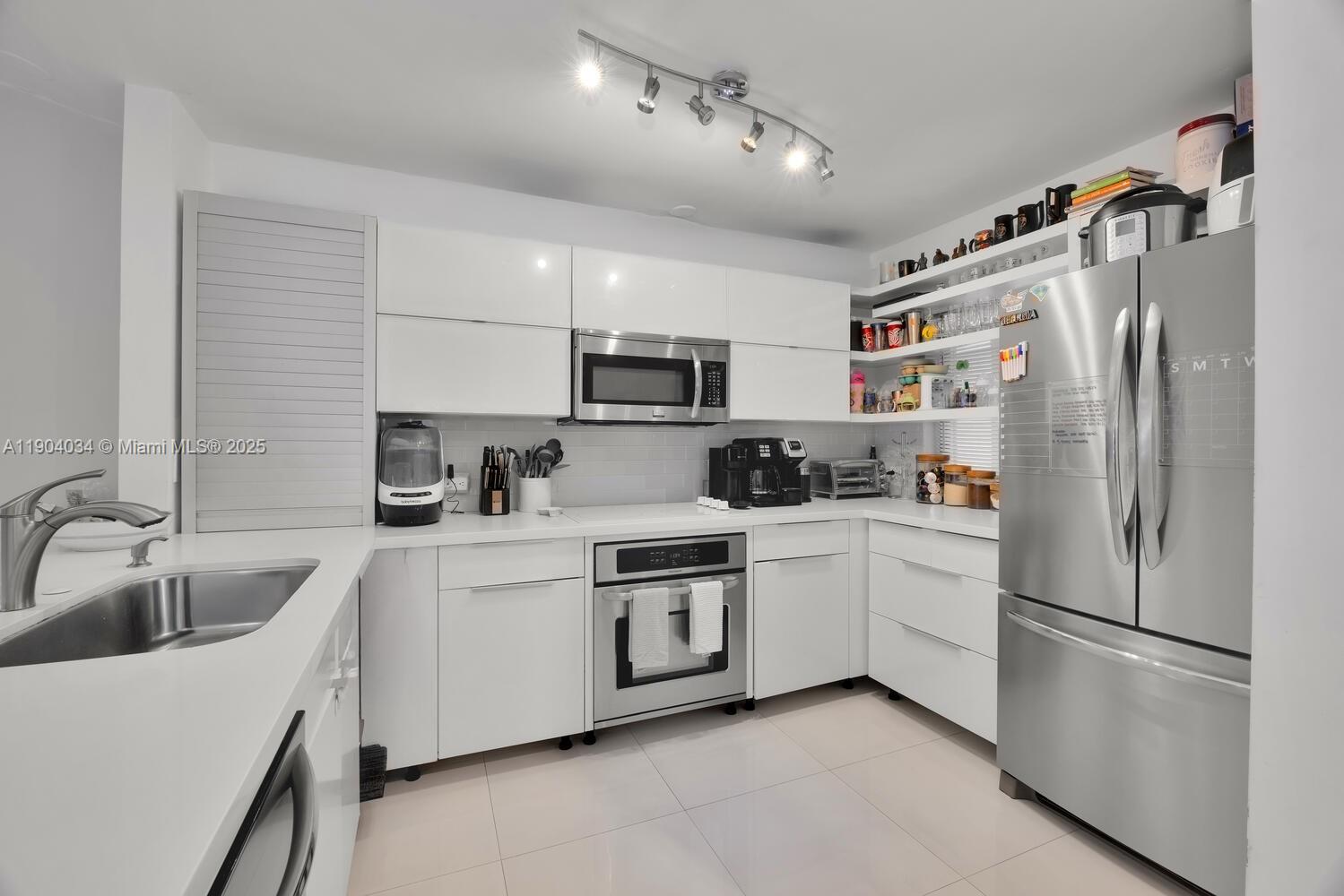8596 Southwest 115th Place Miami, FL 33173 - Photo 8 of 39 a kitchen with a refrigerator a sink and white cabinets