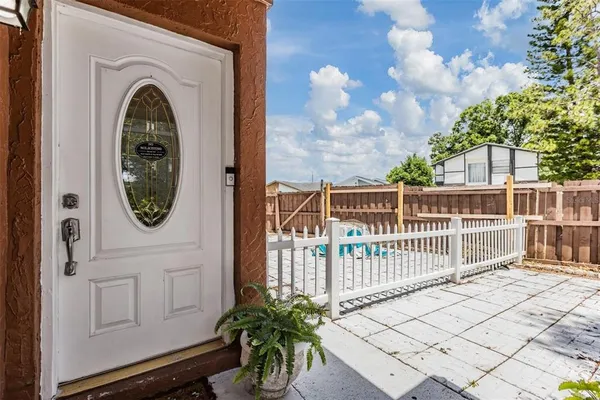 a view of a wooden door with a bench and potted plants