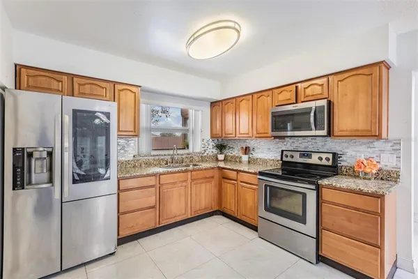 a kitchen with stainless steel appliances granite countertop a stove top oven a refrigerator and a sink
