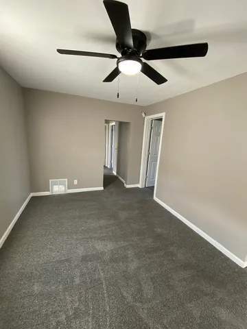 an empty room with a ceiling fan and window