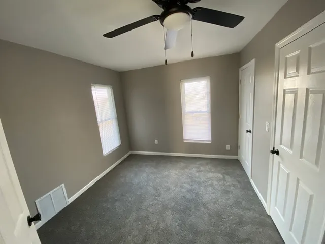 an empty room with windows and fan