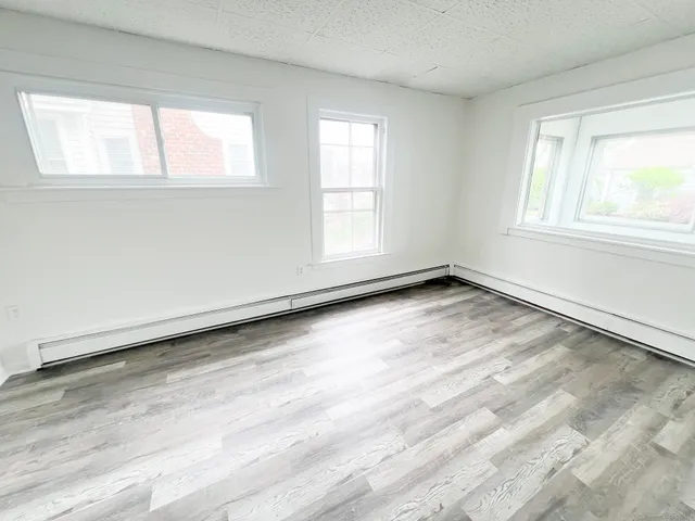 an empty room with wooden floor fireplace and windows
