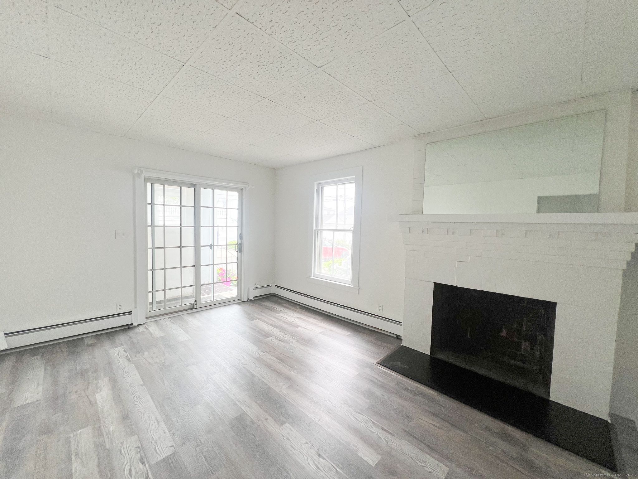 12 Blackall Road, Unit 1 Milford, CT 06460 - Photo 8 of 9 an empty room with wooden floor fireplace and windows