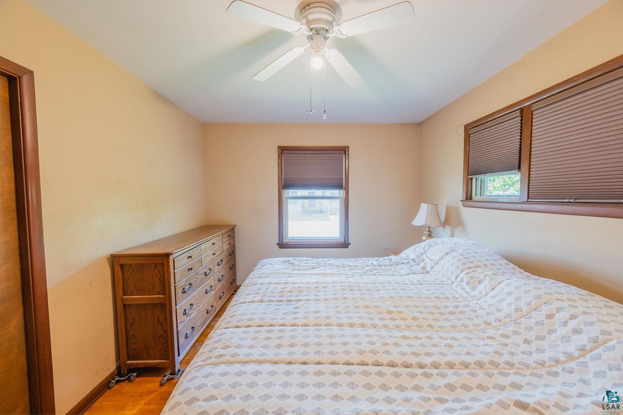101 2nd Avenue North Biwabik, MN 55708 - Photo 12 of 44 Bedroom featuring a ceiling fan with integrated lighting, wood-finish flooring, and multiple windows with blinds