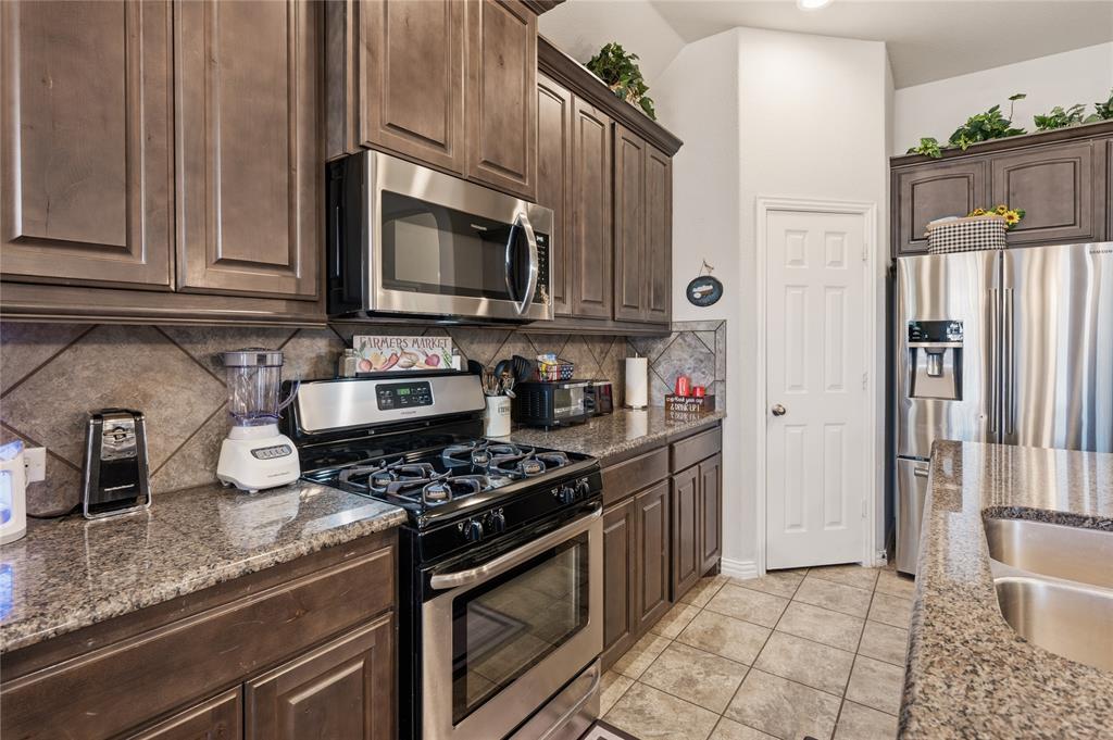140 Chestnut Road Waxahachie, TX 75165 - Photo 13 of 26 Kitchen featuring dark wood-finish cabinetry, granite countertops, stainless steel appliances, and a tile backsplash