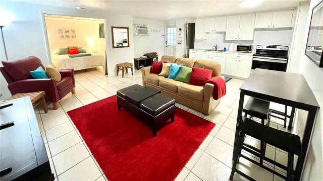 a living room with furniture kitchen view and a wooden floor