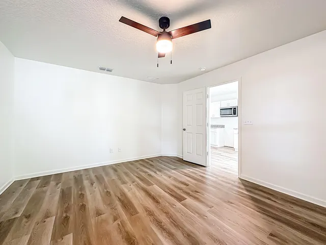 a view of empty room with wooden floor and ceiling fan