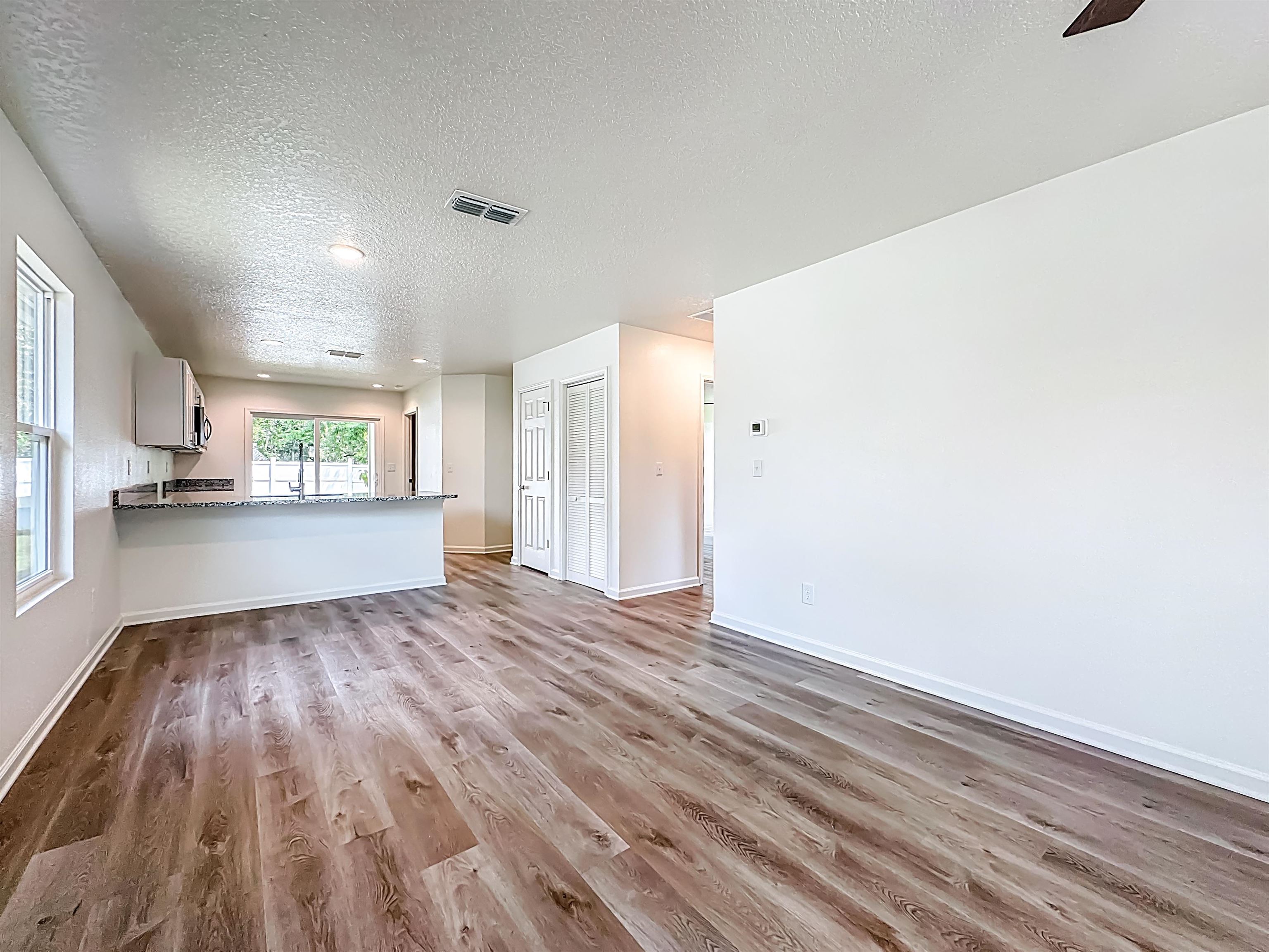 780 West 5th Street St. Augustine, FL 32084 - Photo 3 of 30 a view of an empty room and a kitchen with wooden floor
