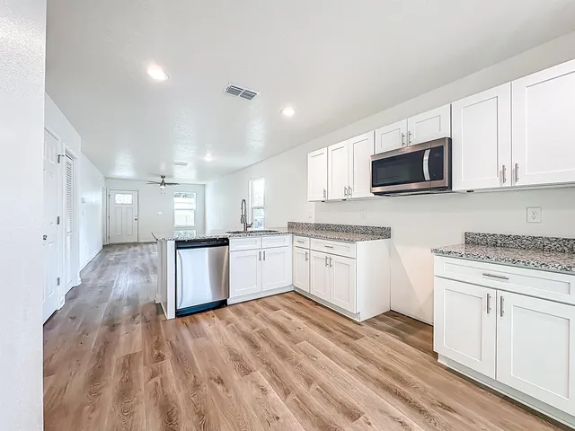 a kitchen with granite countertop white cabinets and white appliances