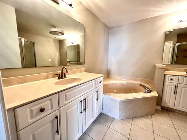 a spacious bathroom with a tub sink and mirror