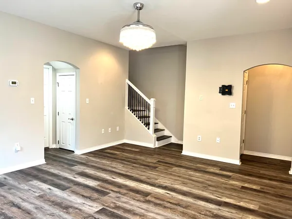 a view of an empty room with wooden floor and staircase