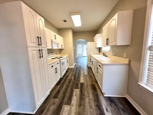 a kitchen with granite countertop white cabinets and white appliances