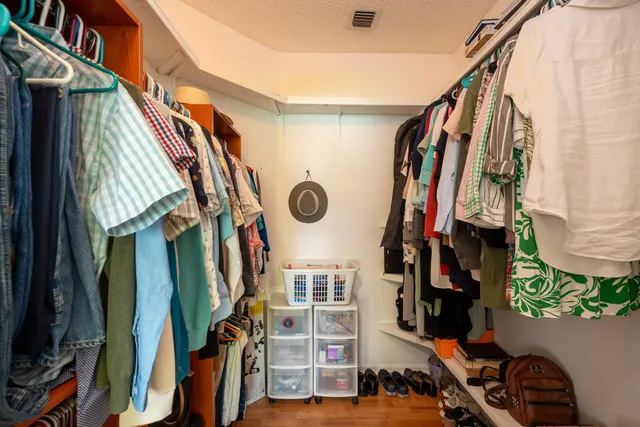 a view of walk in closet with clothes and shoes
