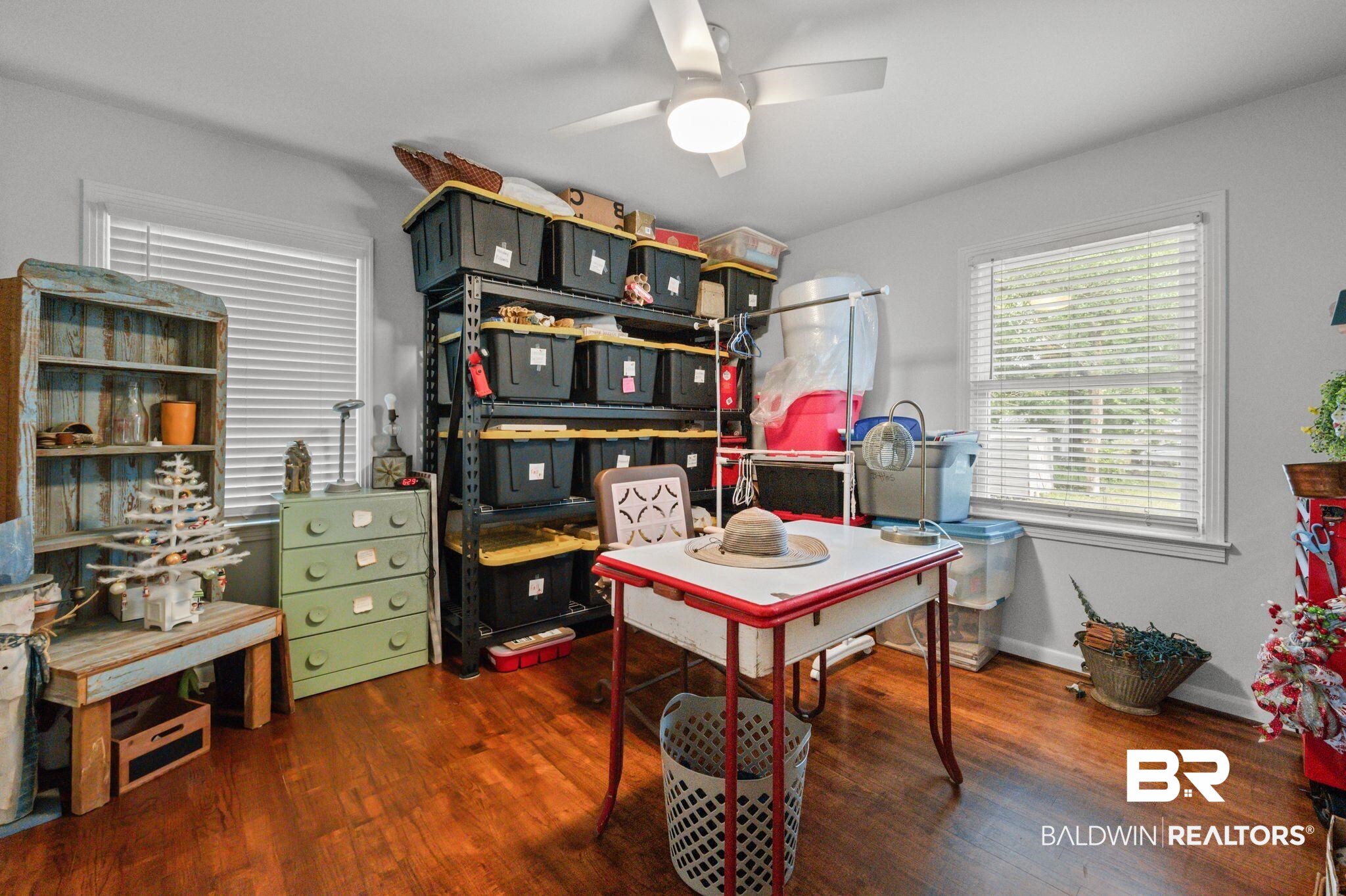 5417 Windmill Drive Mobile, AL 36693 - Photo 19 of 26 Hardwood-finish flooring featuring a white ceiling fan with integrated lighting, two windows with blinds, and light gray wall paint