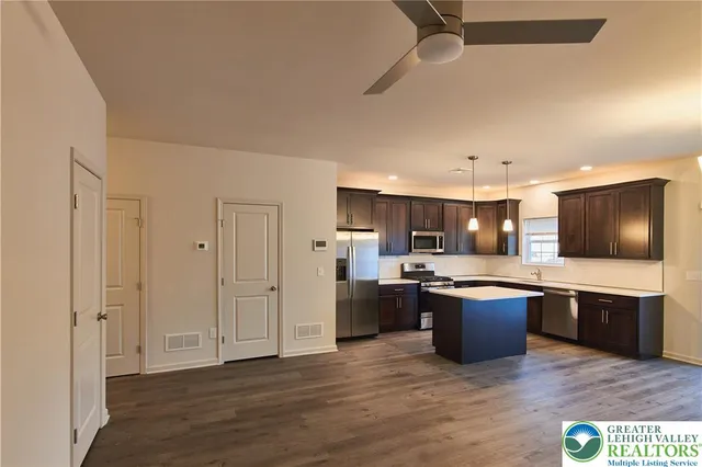 a view of kitchen with stainless steel appliances wooden floor and living room