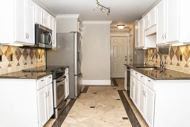 a kitchen with granite countertop a sink stove and refrigerator