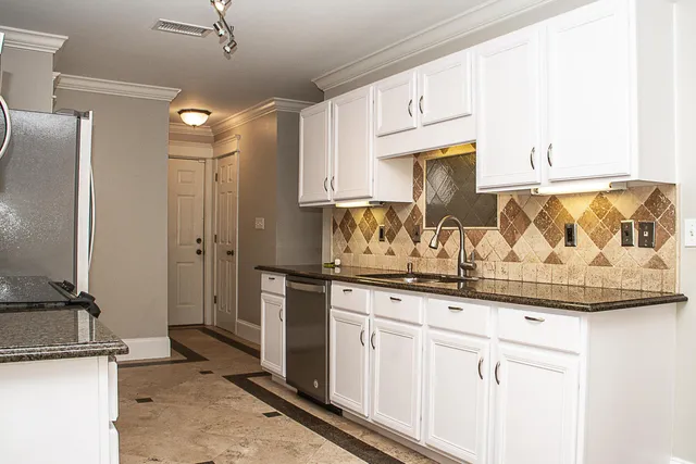 a kitchen with granite countertop a sink stainless steel appliances and cabinets