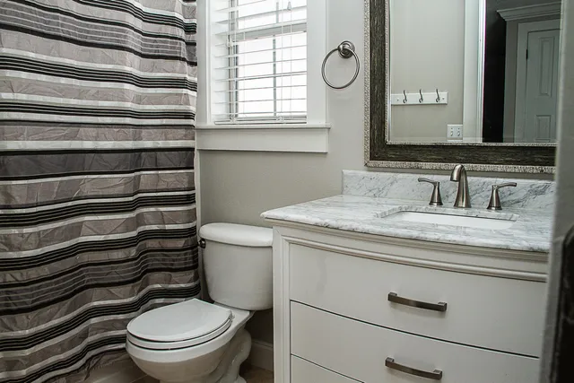 a bathroom with a granite countertop toilet sink and mirror