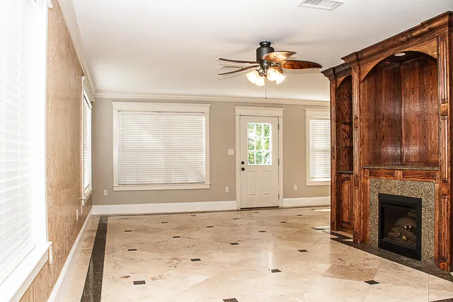 an empty room with windows fireplace and fan