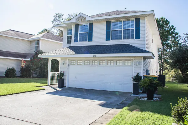 a view of a white house with a yard and plants