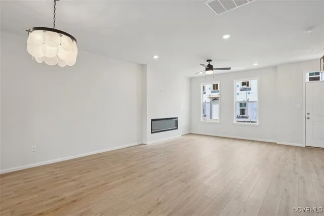 an empty room with wooden floor and kitchen view