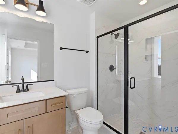 a bathroom with a shower sink vanity mirror and toilet