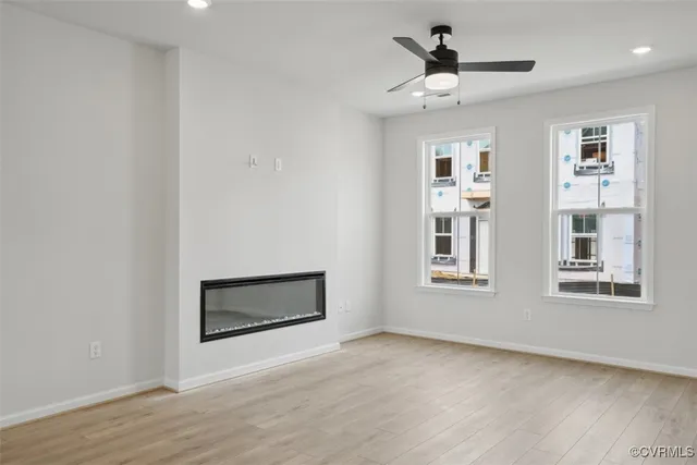 a view of an empty room with a window and wooden floor