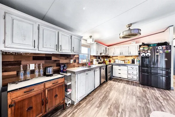 a kitchen with stainless steel appliances kitchen island granite countertop a sink dishwasher stove and oven with wooden cabinets