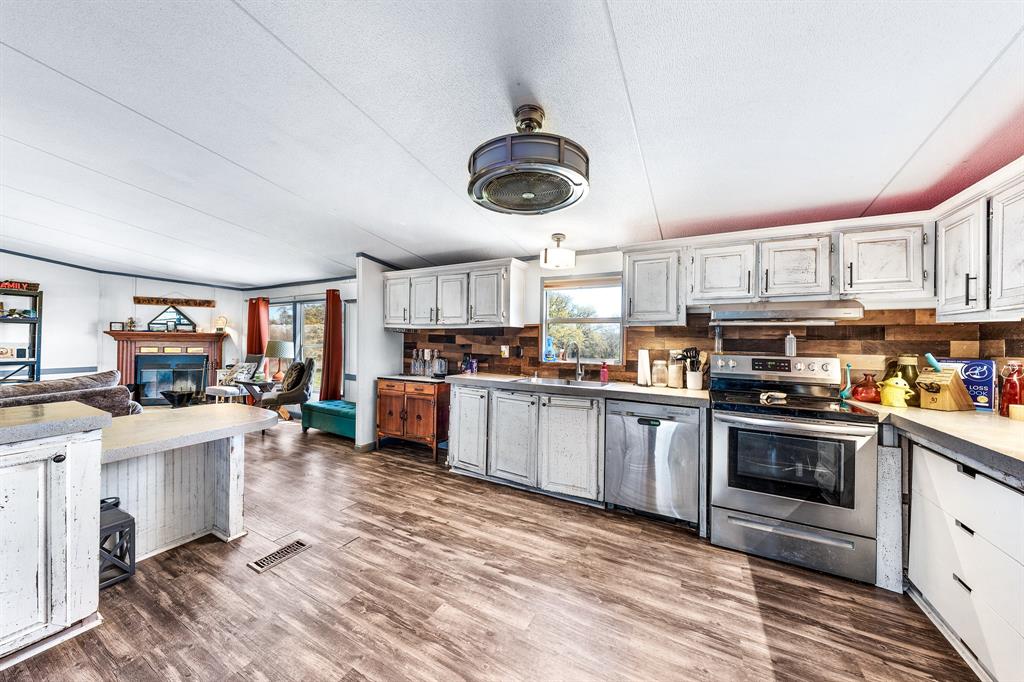 1536 New Hope Road Boyd, TX 76023 - Photo 30 of 40 a kitchen with stainless steel appliances granite countertop a stove top oven a sink dishwasher and white cabinets with wooden floor