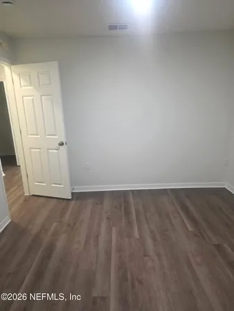 an empty room with wooden floor and white walls