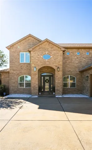 a living room with couches a fireplace and kitchen view with wooden floor