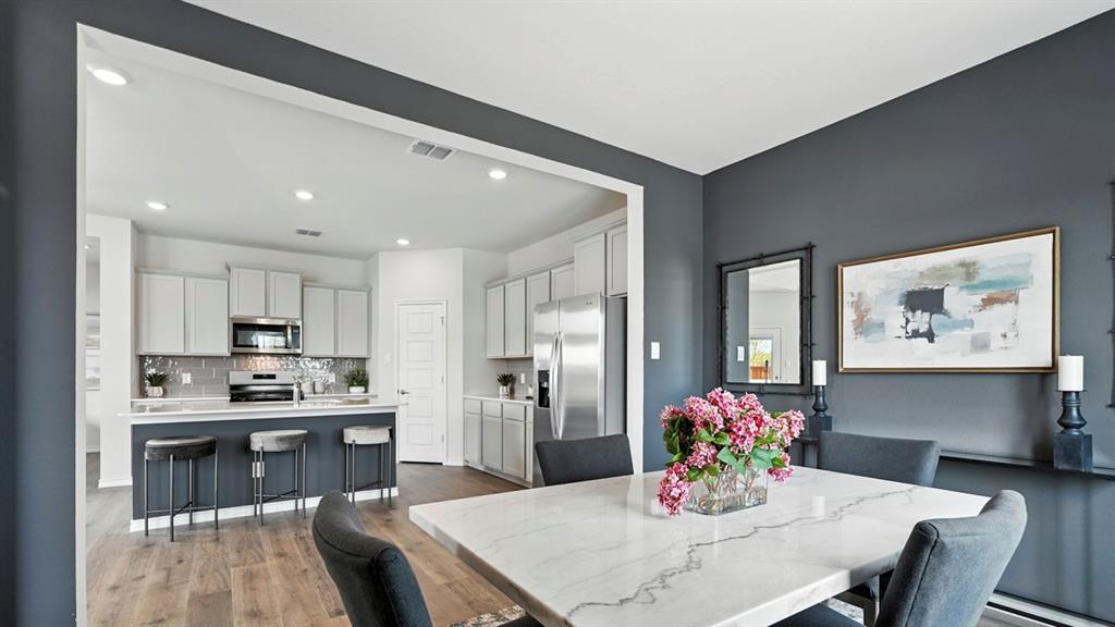 2640 Gladewater Road Celina, TX 75009 - Photo 20 of 40 a kitchen with kitchen island a dining table chairs stainless steel appliances and cabinets