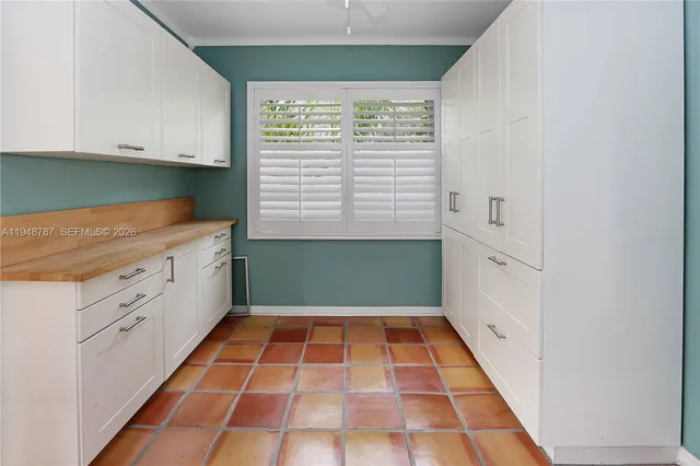 a kitchen with granite countertop a refrigerator a stove and white cabinets with wooden floor