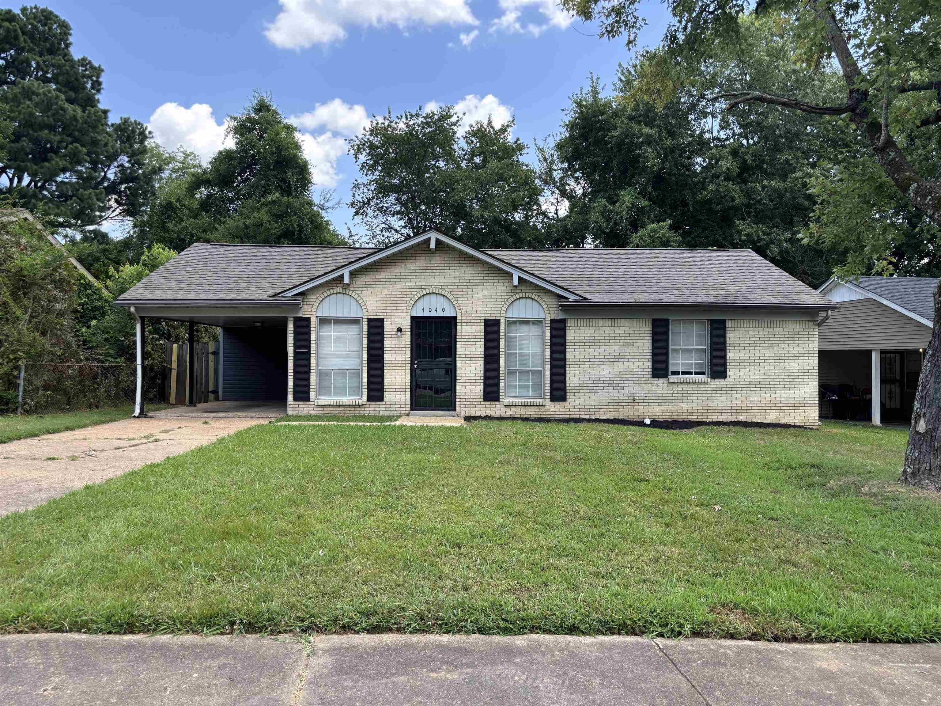 4040 Windermere Road Memphis, TN 38128 - Photo 1 of 14 Ranch-style house with brick siding, a carport, a front yard, driveway, and a shingled roof