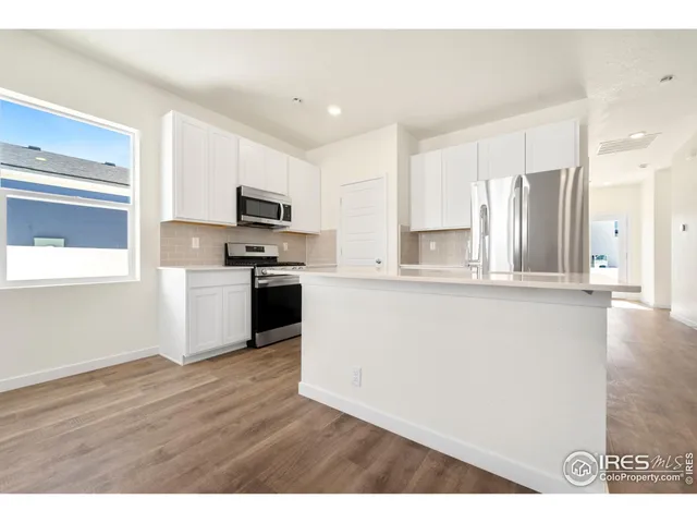 a kitchen with stainless steel appliances granite countertop a refrigerator oven a stove top oven with wooden floor