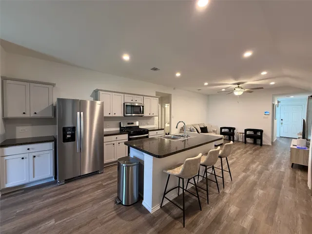 a kitchen with stainless steel appliances kitchen island granite countertop a table chairs stove and refrigerator