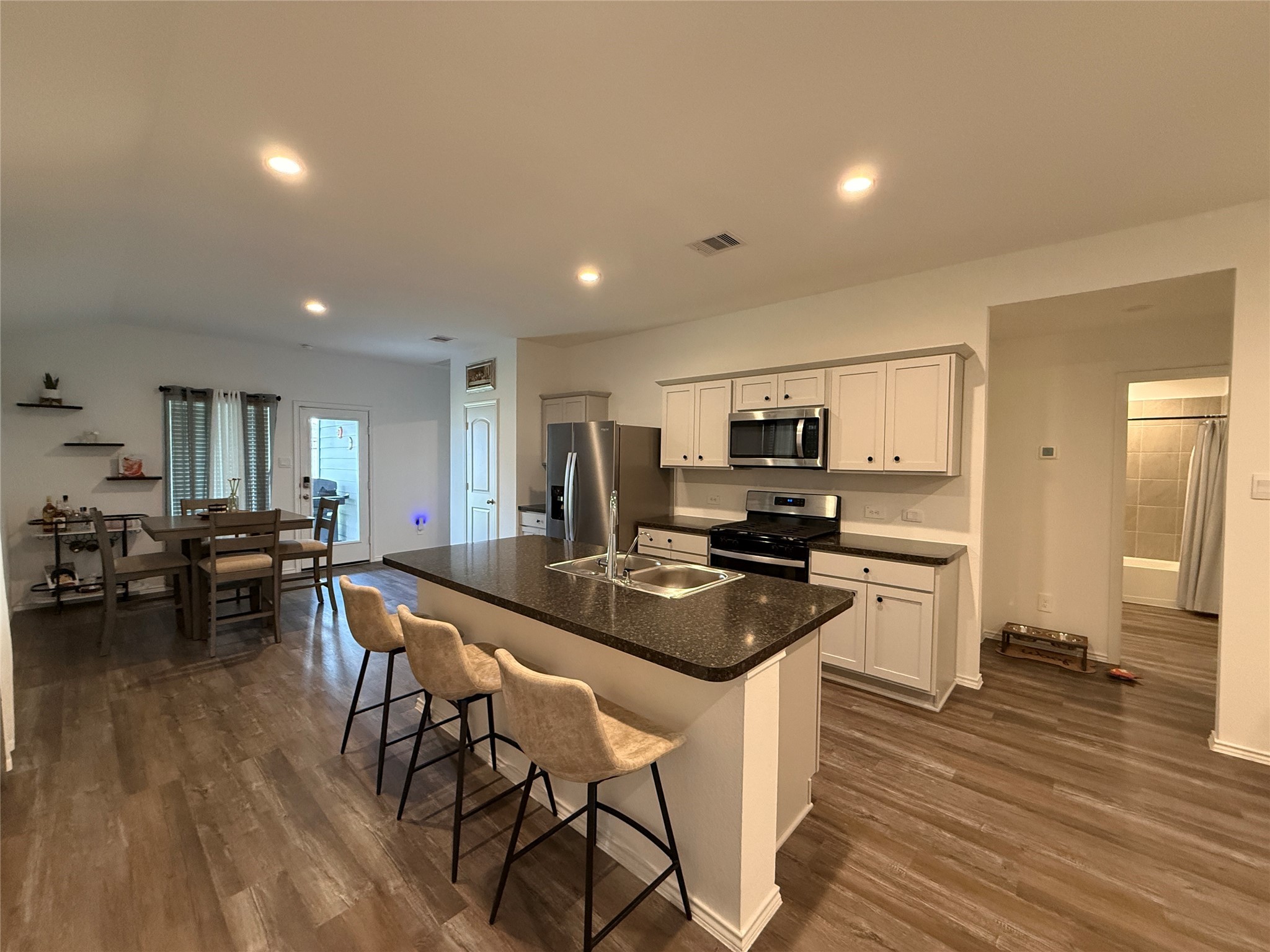 5607 Redstone Gardens Drive Spring, TX 77373 - Photo 4 of 13 a kitchen with stainless steel appliances granite countertop a stove a refrigerator a kitchen island a dining table and chairs with wooden floor