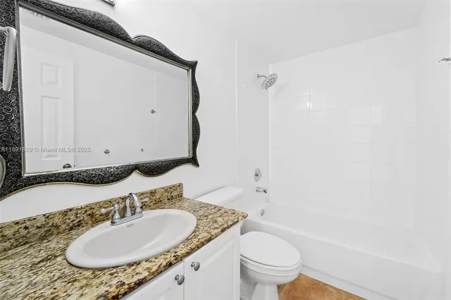 a bathroom with a granite countertop sink toilet and a mirror