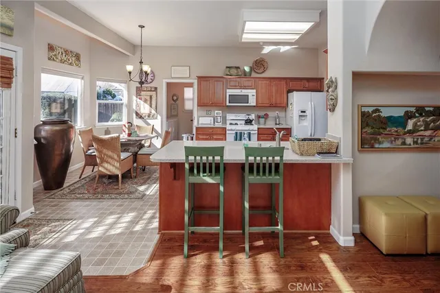 a room with stainless steel appliances kitchen island granite countertop a table chairs and a couch