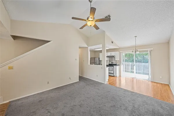 a view of a livingroom with a ceiling fan & refrigerator